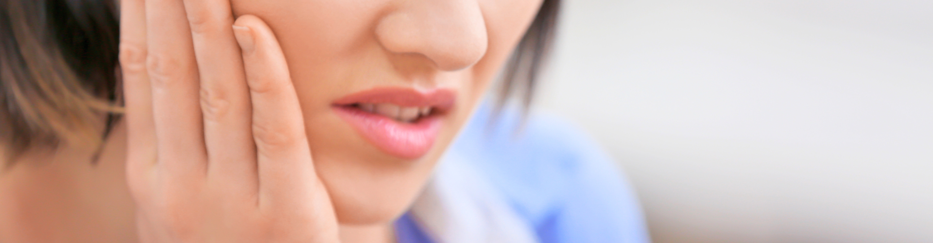 Woman holding her cheek in pain.